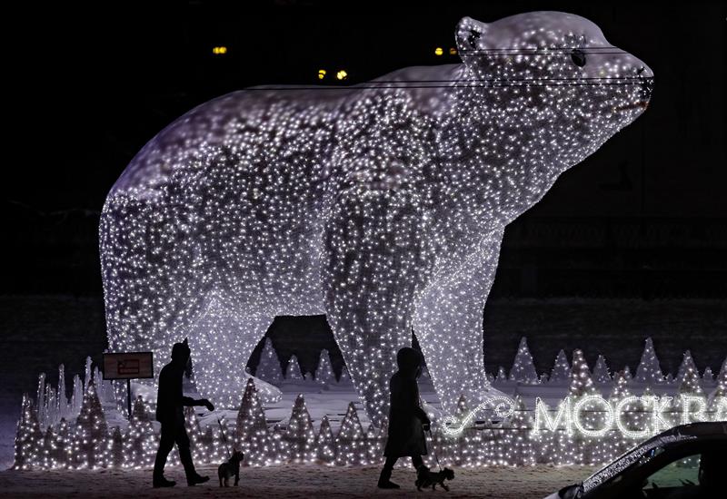 Varias personas caminan junto a un oso gigante de luz en Moscú (Rusia).