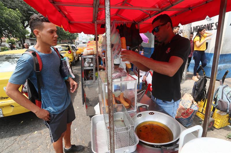 Rodolfo Cruzado (d), un venezolano que lleva cuatro meses vendiendo churros.