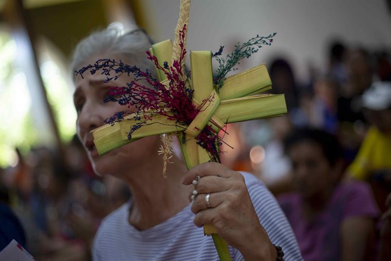 Una mujer con una cruz de palma participa en la procesión del Domingo de Ramos este domingo en Managua (Nicaragua).