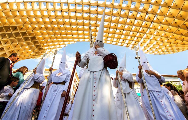 Nazarenos de la hermandad de La Cena a su paso por la plaza de la Encarnación, en la jornada en la que comienzan los desfiles procesionales del Domingo de Ramos en Sevilla.