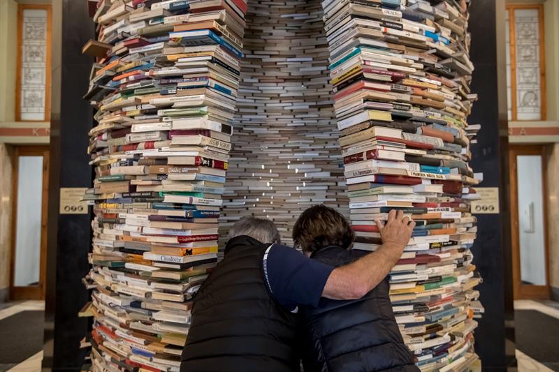 Dos personas observan la escultura titulada "Idioma" del artista eslovaco Matej Kren, una columna hecha de 8.000 libros, expuesta en la entrada de la Biblioteca Central de Praga (República Checa) durante la celebración del Día del Libro. 