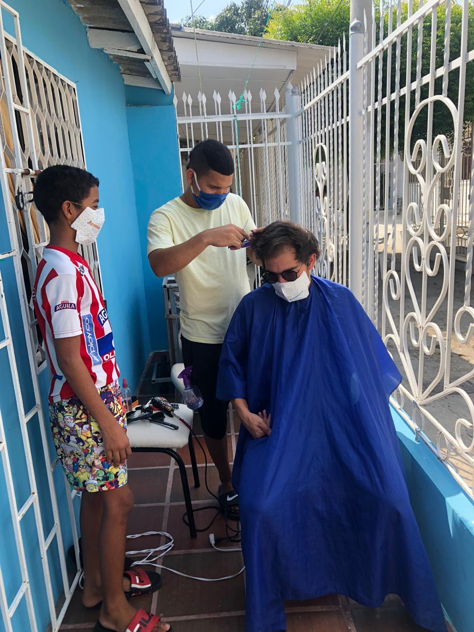 Camus García, motilándose con un barbero del barrio.
