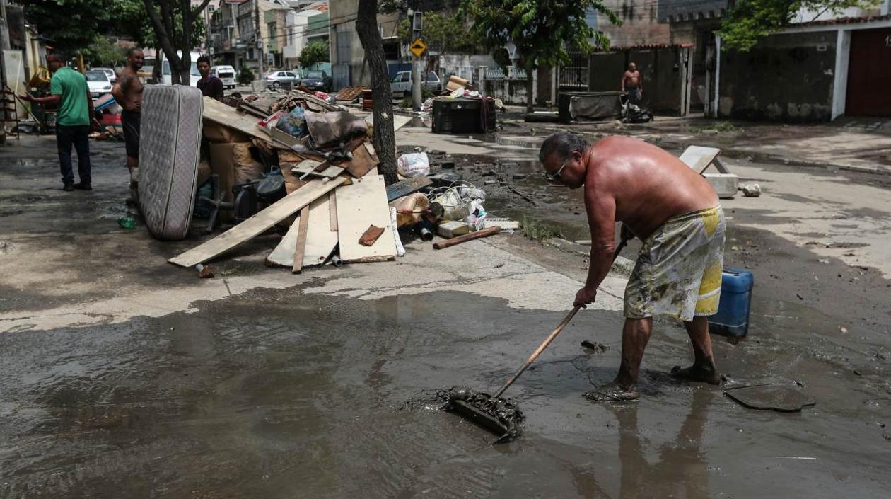 Un hombre limpia una calle afectada por las inundaciones.