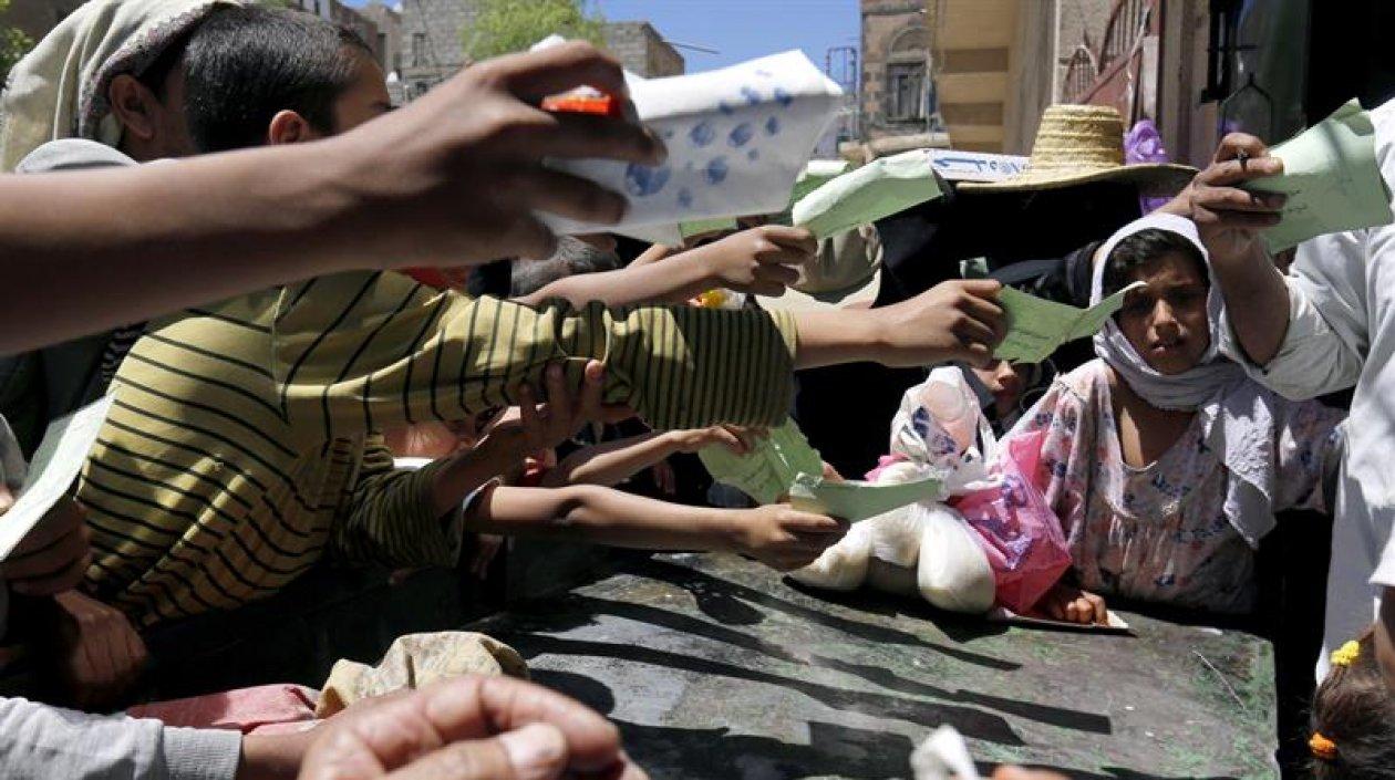 Niños entregan sus cartillas para recibir una ración de comida en un punto de distribución en Saná (Yemen). 