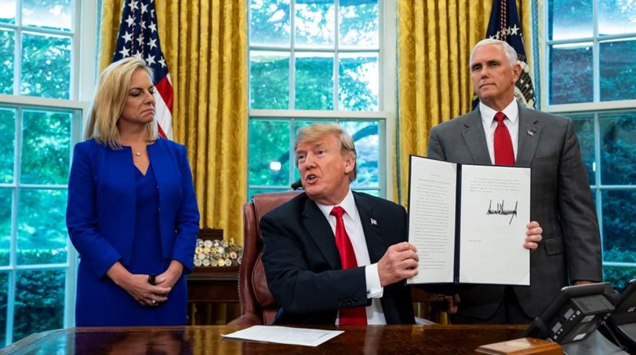 El presidente estadounidense, Donald Trump (c) muestra la orden ejecutiva para detener la separación de los niños inmigrantes de sus padres. 