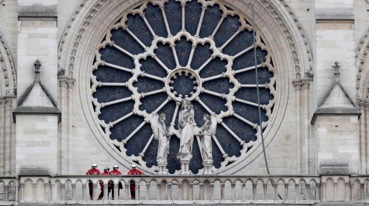 Varios bomberos conversan en un corredor exterior de la catedral de Notre Dame.