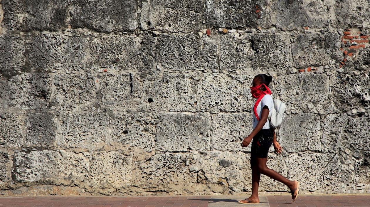 Una joven en Cartagena transita por una de las calles de la ciudad amurallada.