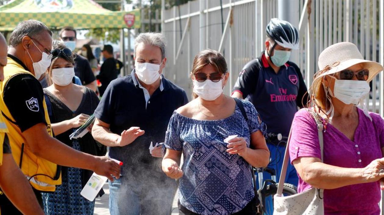 Las autoridades realizan desinfección de las manos a personas que hacen filas en Chile.