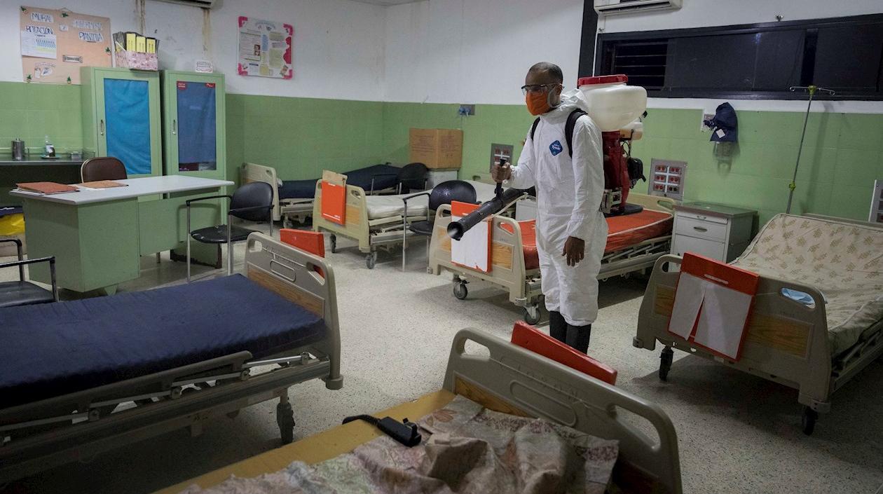 Un miembro de protección civil desinfecta un hospital comunitario.
