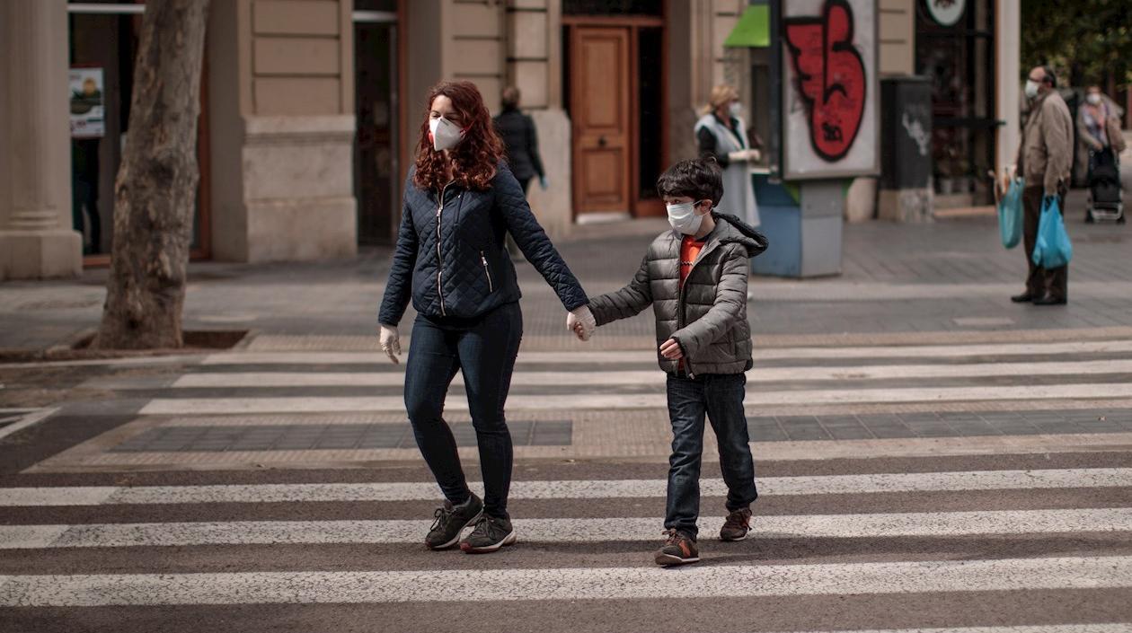 Una mujer acompañada de un niño cruza una calle en Valencia. 