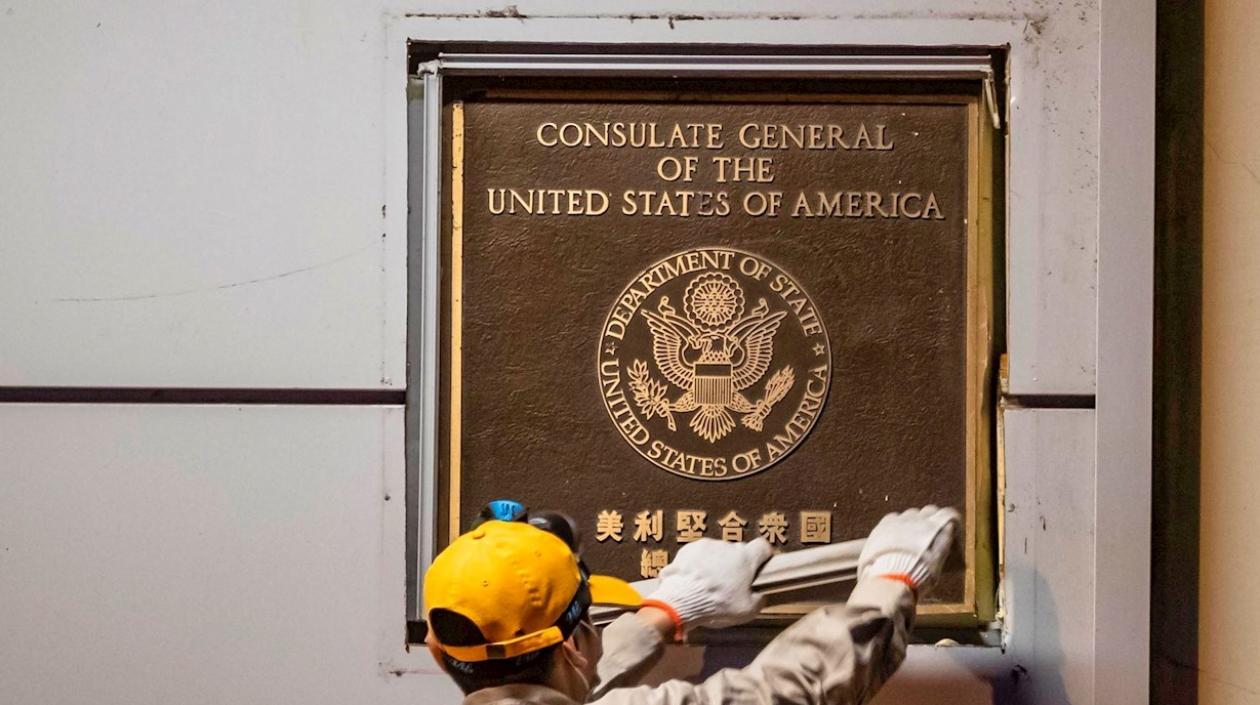 Un hombre intenta quitar la placa frente al consulado estadounidense en Chengdu, capital de la provincia de Sichuan, China.