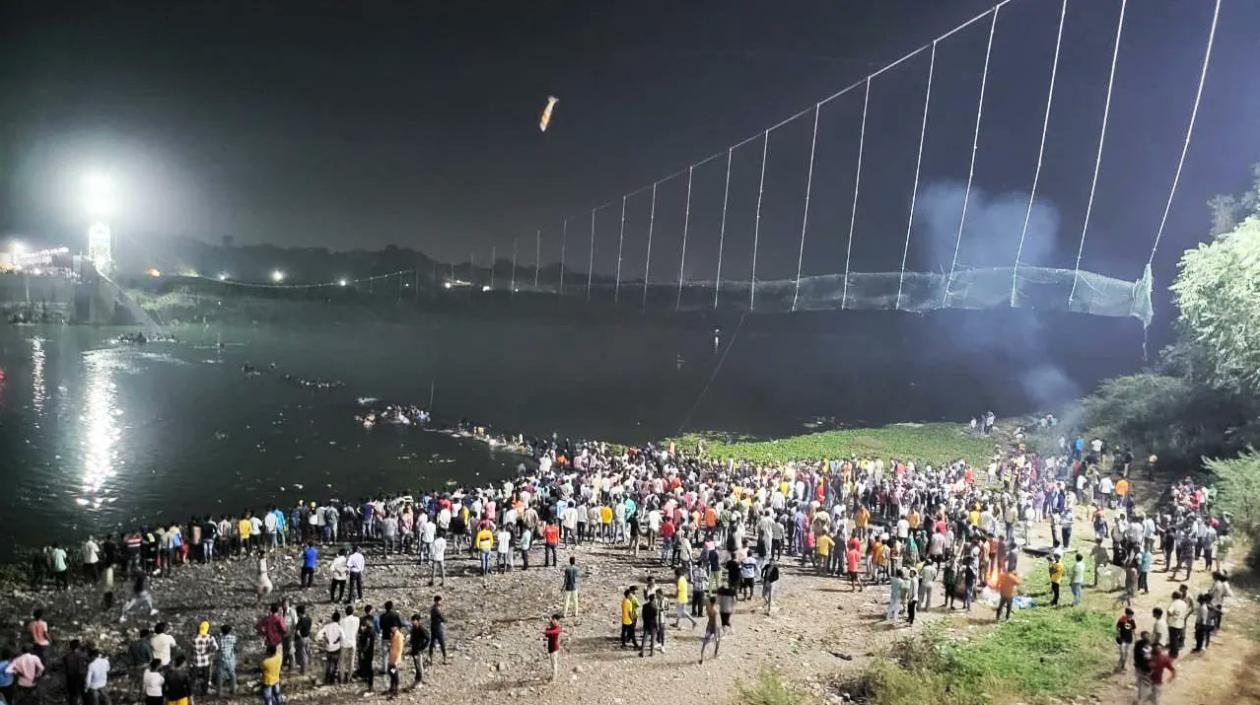 Decenas de personas aguardan luego de que un puente colgante cediera en India.