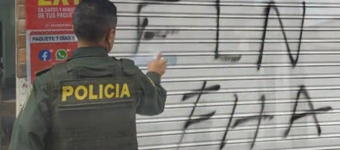 Un policía borra uno de los grafitis del ELN que aparecieron este jueves en Anorí, Antioquia