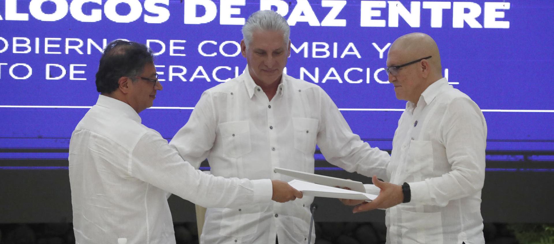 El presidente Gustavo Petro, mientras entrega documentos al jefe máximo de la guerrilla del ELN, Antonio García.  