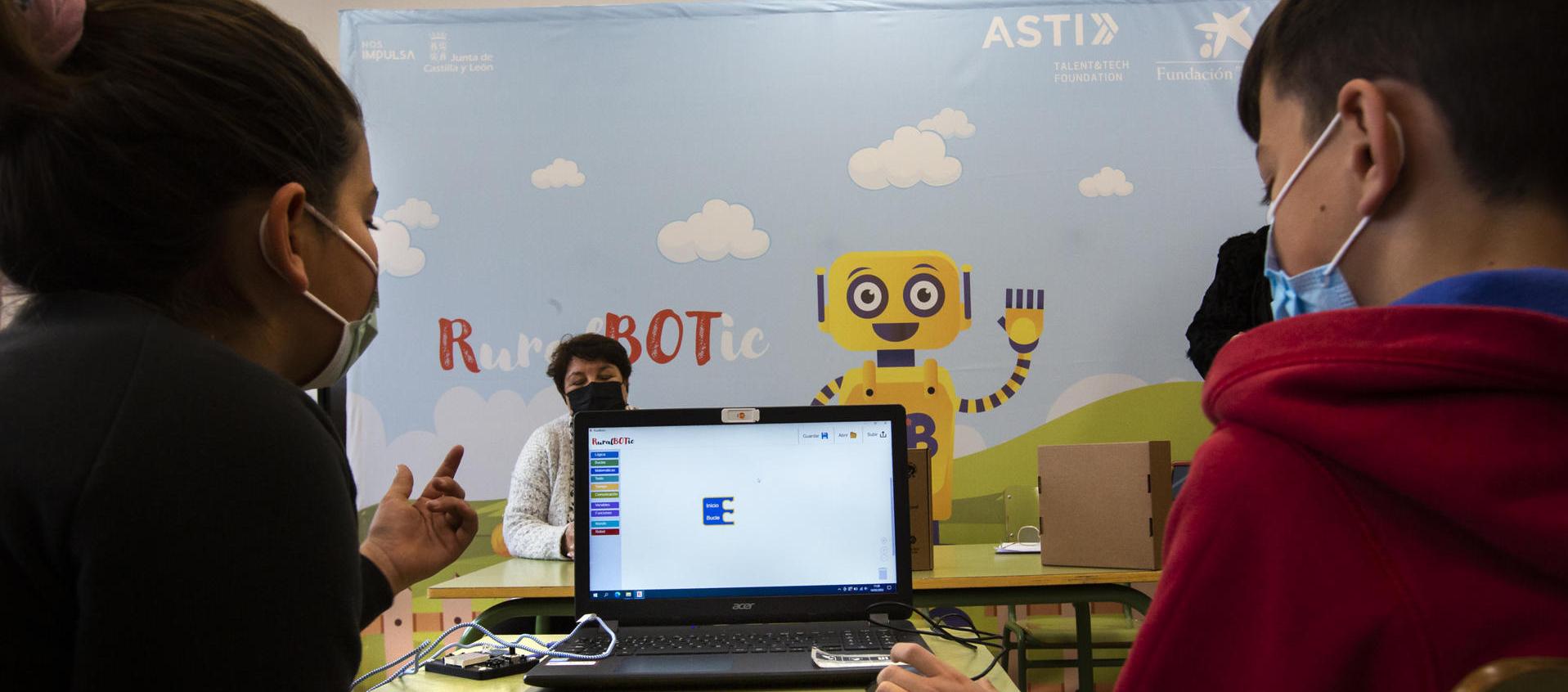 Dos niños manejan un robot por ordenador en un colegio español. 