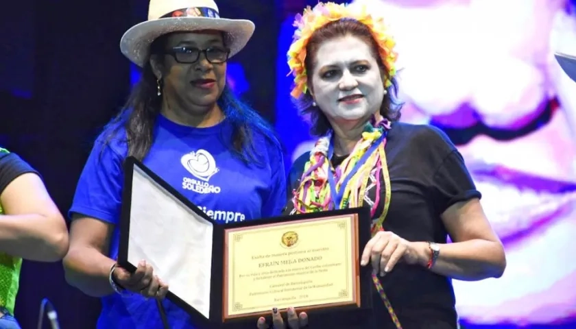 La Gerente de la empresa Carnaval, Carla Celia, entregando el reconocimiento a la hija de Efrain Mejía.