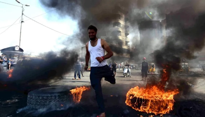 Un manifestante corre entre llantas ardiendo durante una manifestación en la plaza de Khillani en Bagdad, Irak.