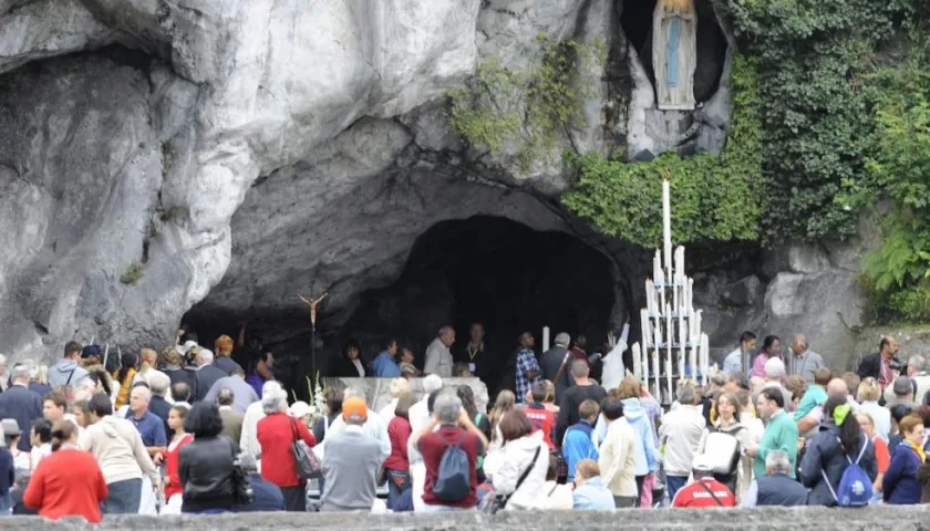 Peregrinos visitan la gruta donde supuestamente apareció la virgen en Lourdes, Francia.