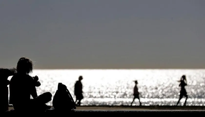 Varias personas disfrutan de un paseo a primera hora en la playa de la Malvarrosa, en Valencia.