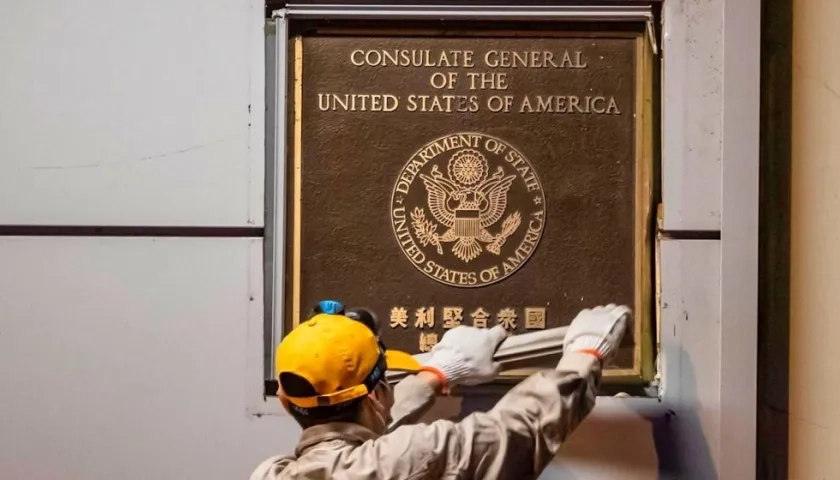 Un hombre intenta quitar la placa frente al consulado estadounidense en Chengdu, capital de la provincia de Sichuan, China.