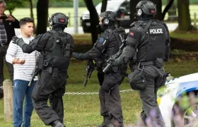 Policías hacen retroceder a personas de la escena de un tiroteo que resultó en múltiples muertes y lesiones, este viernes en Masjid Al Noor en Deans Avenue, en Christchurch (Nueva Zelanda). 