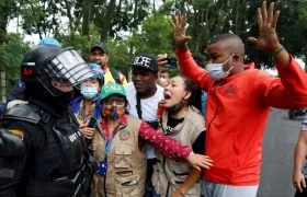 Un efectivo del Escuadrón Móvil Antidisturbios (ESMAD) de la Policía y  manifestantes, en Cali (Colombia). 