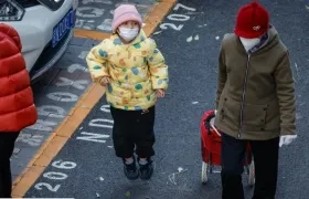 Un niño y una mujer con tapabocas a la salida de un colegio en Pekín