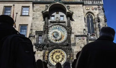 Varias personas observan el reloj astronómico situado en el ayuntamiento de Praga, República Checa.
