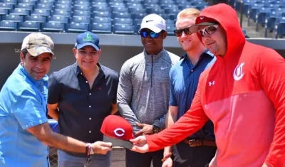Alejandro Char recibe una gorra de la organización de los Rojos de parte de Trey Hendricks.