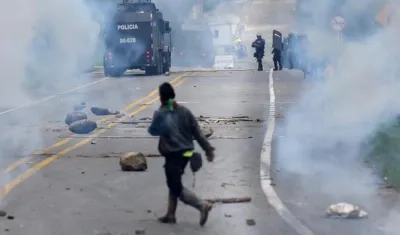 Manifestantes indígenas corren durante un enfrentamiento con el escuadrón antidisturbios de la policía,  en la vía panamericana.