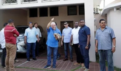 El expresidente de Panamá Ricardo Martinelli (c), rodeado de escoltas privados, saluda mientras sostiene a su perro Martini luego de llegar a su residencia este miércoles.