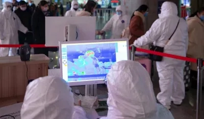 Personal médico utiliza imágenes térmicas visibles e infrarrojas para revisar la temperatura de los pasajeros, en Nanjing (China).. 