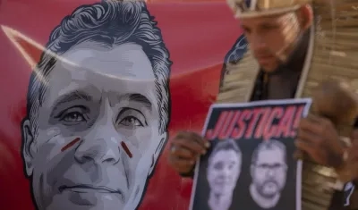 Un hombre sostiene un cartel con retratos del periodista Dom Phillips y el indigenista Bruno Araújo.