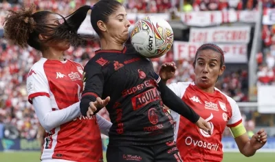 Catalina Usme, capitana del América, protege la pelota ante la marca de dos rivales. 