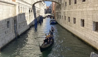 Una pareja disfruta de un viaje en góndola por un canal de Venecia.