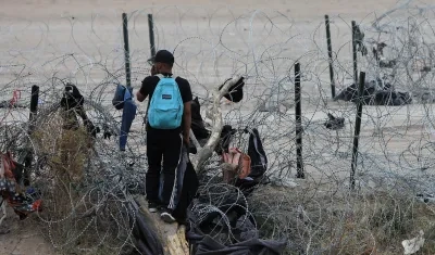 Migrantes buscan cruzar una alambrada en frontera entre México y EE.UU.